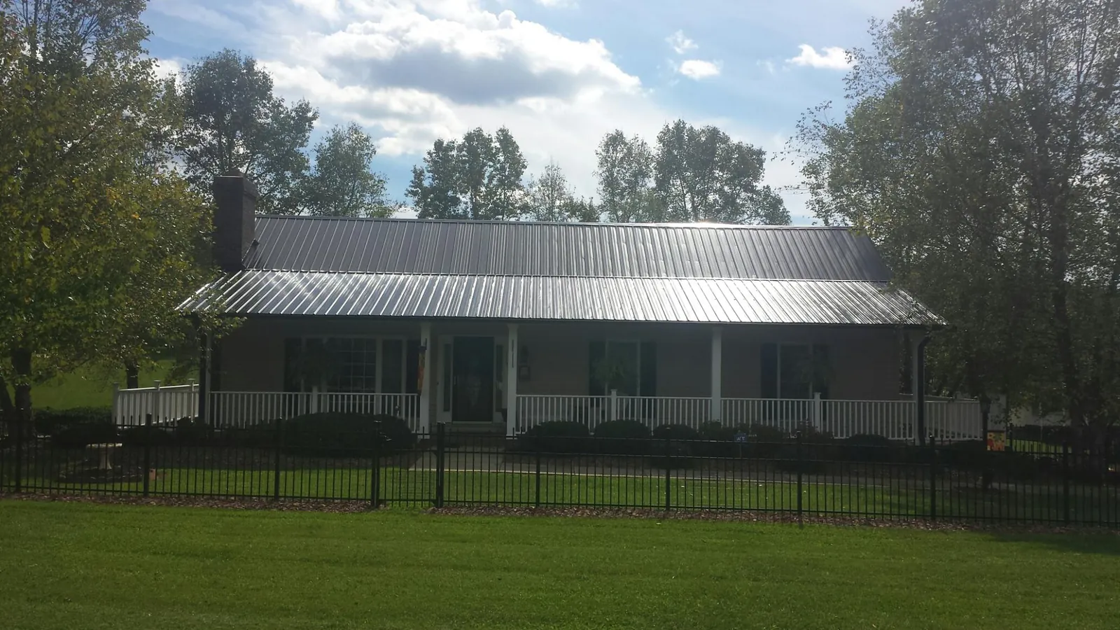 Gray metal roof on a brick ranch with a full width front porch — Gutter Guard Installation work by our crew in Jessup